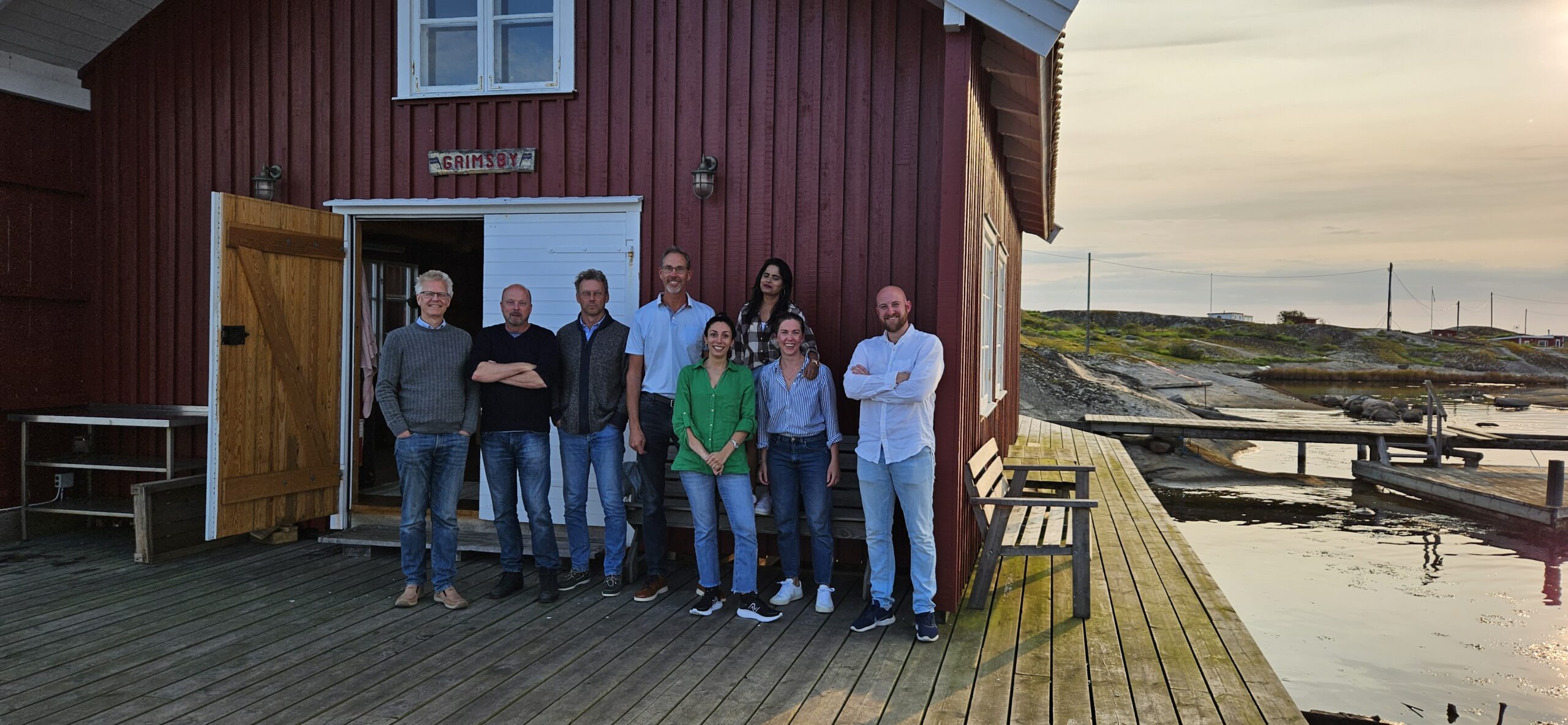 People standing outside a cabin near the ocean